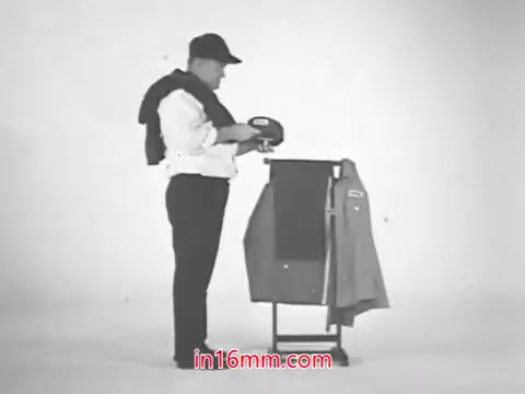 The still features a man dressed in a uniform, preparing to showcase a gasoline pump with a jacket draped over his arm. The scene captures the promotional vibe of the 1960s, accompanied by the voiceover highlighting Total's international experience in blending gasoline. The emphasis is on the brand's commitment to innovation and quality tailored for American consumers.