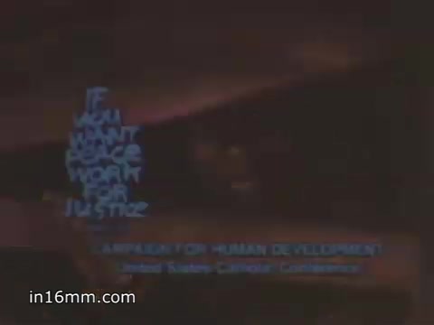 The still features a stylized text that reads 'IF YOU WANT PEACE, WORK FOR JUSTICE,' emphasizing a message of social justice as a pathway to achieving peace. Beneath this, it notes participation in a campaign for human development associated with the United States Catholic Conference. The overall visual aesthetic likely reflects the artistic and political tone of public service announcements from the 1980s.