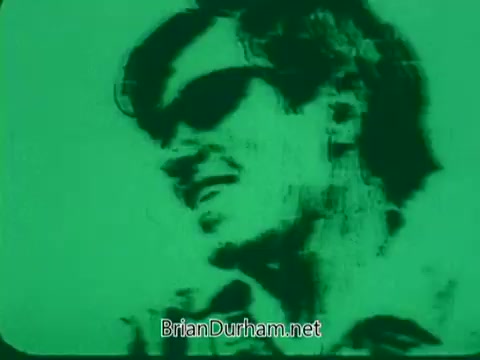 The still features a stylized image of a man with sunglasses, rendered in a green hue that gives it a distinct, surreal appearance. The figure appears to be smiling or in a lighthearted mood, suggesting a sense of enjoyment or creativity. The visual aesthetic likely aligns with the artistic and promotional themes of the 'Pittsburgh Symphony Promenades' project.