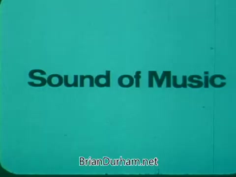 The still features a simple typographic display reading 'Sound of Music' against a turquoise background. The text is bold and prominent, likely serving as a promotional element for the Pittsburgh Symphony's 'Promenades' program. The overall aesthetic reflects a vintage style typical of 16mm film.