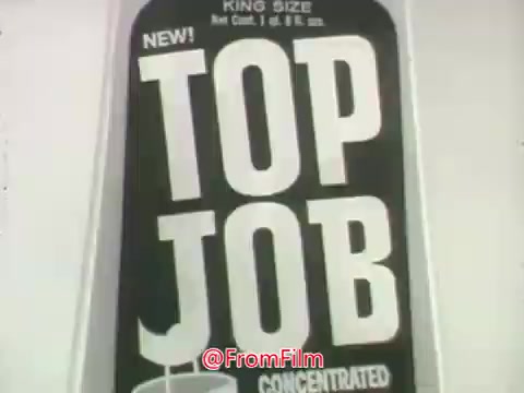 The still features a package of 'Top Job,' a bright green ammonia cleaner from Procter and Gamble. The label prominently displays 'NEW!' and 'KING SIZE' along with 'CONCENTRATED.' It emphasizes the product's effectiveness in cleaning floors, as depicted in the accompanying dialogue between a couple discussing the dullness of their floor and the benefits of using this cleaner.