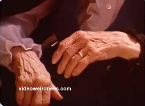The still features two elderly hands, showcasing their age and intricacy with visible wrinkles and a wedding ring on one. The focus on these hands likely symbolizes care, compassion, or support, aligning with the humanitarian themes of the Red Cross PSA. The composition emphasizes connection and the human experience.