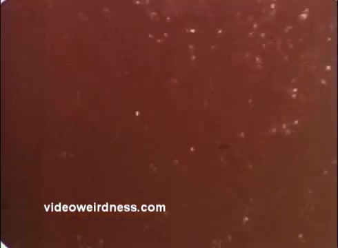 The still features a textured, reddish-brown background with scattered light particles, possibly simulating a warm or organic environment. Given its context as a Red Cross PSA, it likely serves as a visual metaphor for health, care, or community wellbeing. The overall tone appears vintage, typical of mid-20th century public service announcements.