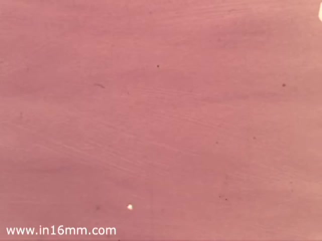 The 16mm still from the Canada Dry Buffalo Sabres commercial features a predominantly pink background with subtle texture. There is a small white dot visible, likely a flaw or artifact from the film print. The overall appearance suggests a vintage quality, typical of the 1970s era.