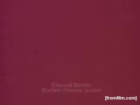 The still from the 'Borden American Cheese' commercial features a strongly faded red background. At the center, there is text that reads 'Elwood Binder, Borden cheese grader.' The overall appearance suggests significant color deterioration typical of older 16mm films, with limited visibility of original colors, primarily dominated by red hues.