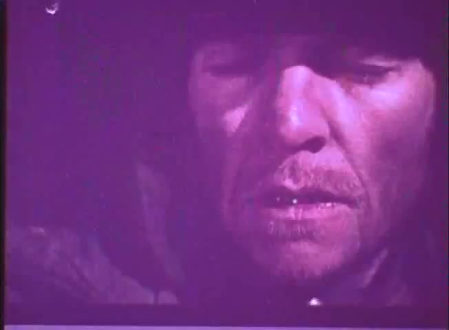 The still from the trailer of 'One Day in the Life of Ivan Denisovich' features a close-up of a man, likely portraying Ivan Denisovich. His expression reflects weariness and contemplation, highlighting the hardships faced in a labor camp. The image exhibits a desaturated color palette, contributing to a somber and stark mood consistent with the film's themes of survival and resilience.