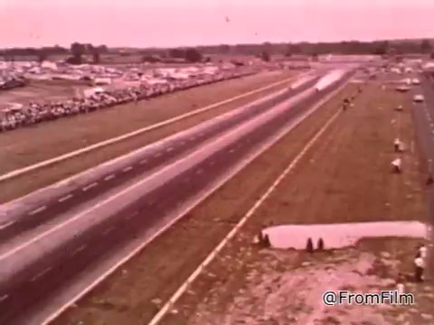 The still from 'Dragsters and Cars' features a drag racing scene, likely from the 1960s, showcasing a wide, open track lined with spectators. The focus is on the importance of car maintenance for achieving success in drag racing, with Don Garlits emphasizing the need for peak vehicle performance to win races.   As for the Dodge in the video, exact identification may require more specific details or context about the model visible in the footage.