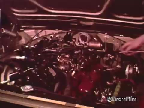 The still from the 16mm film 'Dragsters and Cars' features the engine compartment of a Dodge vehicle, showcasing detailed maintenance work. Don Garlits emphasizes the importance of keeping a car in top condition for drag racing success. The specific year of the Dodge can't be determined definitively, but vehicles from the 1960s are common in this context.