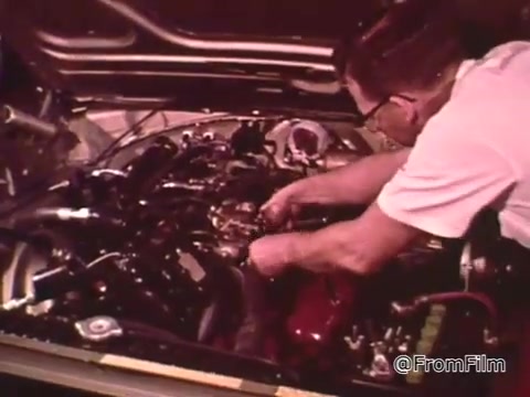 The still features a mechanic working on a car's engine, likely during a maintenance or tuning session. The context suggests it’s focused on performance, highlighting the importance of keeping a race car in top condition for drag racing. The vehicle appears to be a Dodge, typical of the era, possibly from the late 1960s. The emphasis in the voice-over indicates that Don Garlits, a prominent drag racer, is sharing insights on achieving success in drag racing through proper vehicle maintenance.