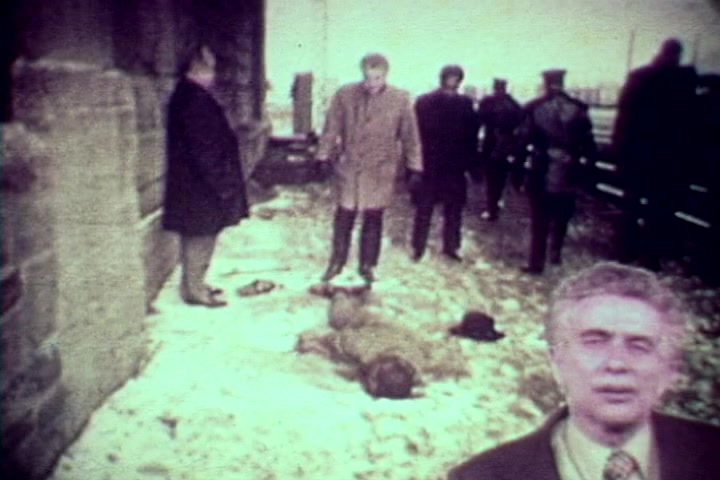 The still from 'Drug Abuse: Some Comments from the Morgue' features a grim scene outside, with several individuals, including figures in overcoats and police uniforms, gathered around a snowy area. In the foreground, Tillman Hahn, the medical examiner, appears to address the camera. Two lifeless bodies lie on the ground, emphasizing the stark impact of drug abuse. The overall mood is somber, reflecting the film's anti-drug message and the harsh realities of addiction.