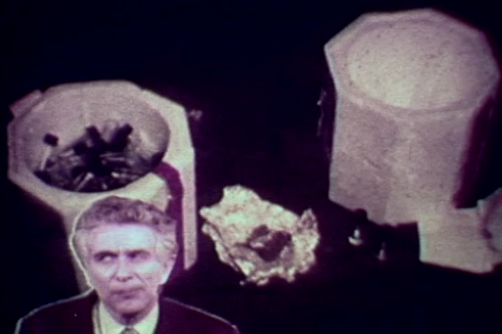 The still depicts a scene from the anti-drug film 'Drug Abuse: Some Comments from the Morgue.' In the foreground, a man, likely Tillman Hahn of the Medical Examiner’s office, is speaking, conveying a serious tone. Behind him, there are various drug paraphernalia items, including containers and evidence of substance use, emphasizing the film's grim subject matter regarding the consequences of drug abuse. The image likely aims to educate viewers on the dangers of drugs through stark visuals and testimony.