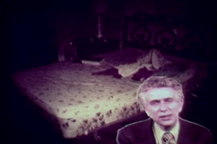 The still features a dimly lit bedroom with an unmade bed, partially covered with a blanket. In the foreground, Tillman Hahn from the Medical Examiner's office speaks directly to the camera, providing commentary on the harrowing impacts of drug abuse. The overall mood is somber and reflective, emphasizing the stark realities of addiction as depicted in the 1970s anti-drug film 'Drug Abuse: Some Comments from the Morgue.'
