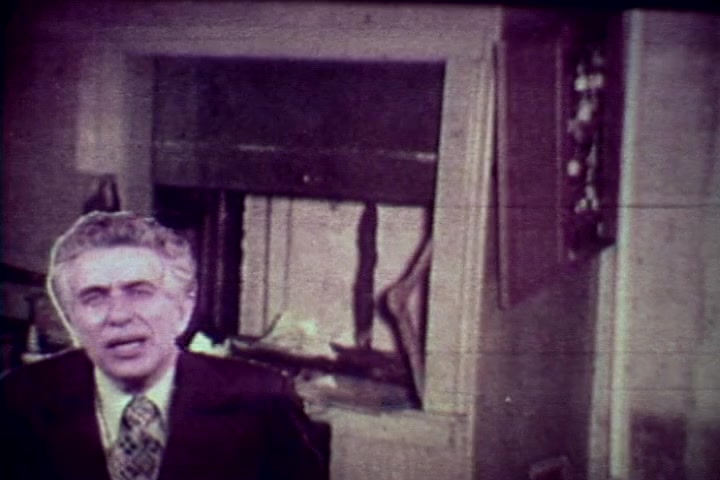 The still features Tillman Hahn, a medical examiner, delivering a serious message about drug abuse. He is positioned in the foreground with a concerned expression, likely discussing the impacts of addiction. In the background, a morgue setting is suggested, hinting at the grim consequences of drug use. The 16mm film grain adds a vintage quality, typical of 1970s anti-drug campaigns. The overall tone is somber and reflective, aimed at conveying a cautionary message.