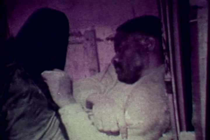 The still from 'Drug Abuse: Some comments from the morgue' depicts a somber scene typical of 1970s anti-drug films. It shows a deceased individual in a morgue setting, underscoring the grave consequences of drug abuse. The color tone leans towards muted and possibly faded hues, reflective of the film's vintage format. This imagery serves to evoke a strong emotional response, emphasizing the tragic reality of drug-related deaths.