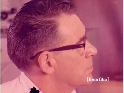 The 16mm still from 'Bell System - Preventing Data Transmission Errors' features a profile view of a man with glasses and neatly styled hair. He appears to be engaged in a technical environment, likely related to computer engineering or telecommunications. The film, a silent piece from 1967, visually explores themes of data transmission with scenes of engineers, computers, and oscilloscope footage. However, this specific still may show a lab defect, suggesting a potential issue with the film quality.