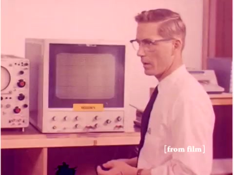 The still features a male engineer in a white shirt and tie, standing next to an oscilloscope. The oscilloscope displays a grid or waveform, typical of the era's technology. In the background, there are additional pieces of equipment, likely used for data transmission or testing. The image reflects a mid-20th-century scientific environment, consistent with the film's focus on preventing data transmission errors. The aesthetic has a vintage quality, indicative of the 1960s era.