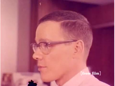 The still features a profile shot of a man in glasses, likely an engineer, set against a background that suggests a professional office environment. The colors appear muted and slightly faded, typical of older film negatives. The context indicates it’s part of a Bell System film from 1967, focusing on data transmission technology, and reflects the era’s styles in both fashion and film presentation. The presence of lab defects suggests imperfections in the film stock, which adds historical authenticity to the piece.