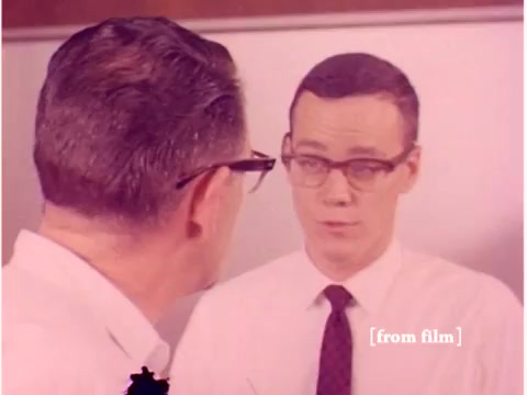 The still shows two men in a conversation, possibly in a laboratory or office setting. One man has glasses and is facing a mirror or reflective surface, suggesting he is speaking to himself or reflecting on a discussion. Both are dressed in professional attire, typical of the era. The film appears to be a silent educational piece focusing on technology, likely related to preventing data transmission errors, as indicated by the title. The image is part of a lab defect, affecting its clarity and presentation.