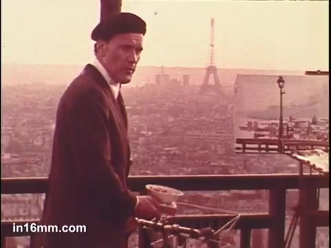 The still from the 'Birdseye Frozen Parisian Vegetables' commercial features a man in a beret, standing against a picturesque backdrop of Paris, including the Eiffel Tower. He is holding a bowl, possibly showcasing the frozen vegetables. The scene has a warm, nostalgic tone, highlighting the connection between French culture and quality food, while emphasizing the allure of the city.