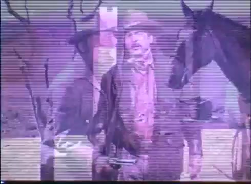 The still from the 'Showdown' trailer features two male characters, likely Dean Martin and Rock Hudson, dressed in Western attire, complete with hats and rugged clothing. One figure stands in the foreground, while the other is partially visible behind him, adding depth to the shot. A horse is seen nearby, enhancing the Western theme. The image has a vintage quality, likely due to the 16mm format, and displays some visual artifacts typical of older film prints. The overall mood suggests a tense or dramatic moment characteristic of classic Westerns.