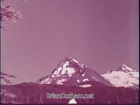 The still features a serene landscape showcasing snow-capped mountains against a clear sky. The coloration suggests a vintage feel, typical of mid-20th-century film. This frame is likely part of a promotional piece highlighting America's natural beauty in the 1969 'Discover America' PSA.