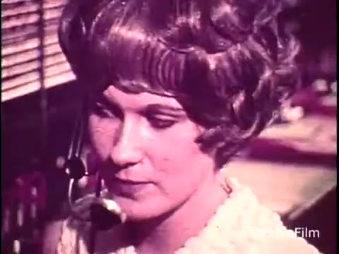 The still features a telephone operator from a C&P Telephone commercial, likely from the early 1970s. She is focused and wearing a headset, characteristic of the era’s communication style. The background hints at a busy switchboard operation, emphasizing the hands-on nature of long-distance dialing. The vintage aesthetic reflects the technological context of the time.   Follow us on Twitter @FromFilm.