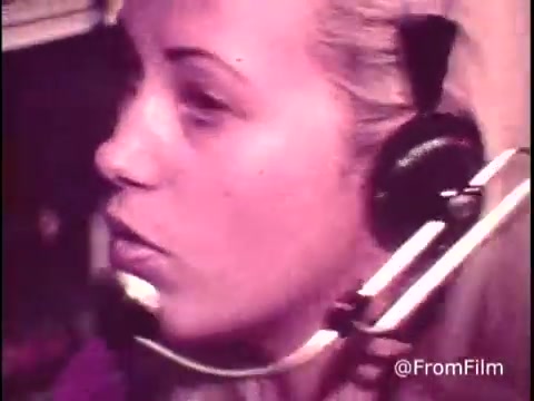 The still from the C&P Telephone commercial features a female telephone operator using a headset with a mouthpiece. She appears focused on her work, likely assisting customers with long-distance dialing. The visual style is indicative of the early 1970s, capturing the era's aesthetic and technology. The scene reflects the human element in telephone communication before the widespread adoption of direct dialing.   Follow @FromFilm for more insights!