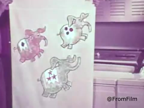 The still features a person holding a fabric showcasing colorful elephant designs, likely promoting Rinso Detergent with color bleach capabilities. The elephants are stylized, with various colors and patterns, highlighting the detergent's effectiveness in maintaining vibrancy. The setting appears to be a vintage kitchen with a washing machine in the background, indicative of 1960s domestic life. This ad encapsulates the era’s focus on household products that care for clothing and colors.    for more vintage insights!