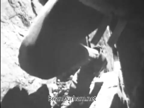 The still shows a close-up of a soldier's leg and boot as they navigate rocky terrain, suggesting an emphasis on physical activity or training. The black-and-white imagery reflects the era of the 1960s Army ROTC at Fort Monroe, VA. The composition focuses on the soldier's movement, conveying a sense of action and determination.