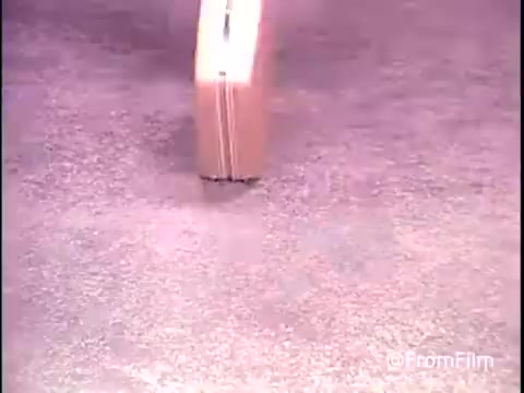 The still from the 1979 Samsonite luggage commercial features a close-up shot of a suitcase. The suitcase is shown rolling smoothly across a textured surface, highlighting its durability and mobility. The lighting emphasizes its design, showcasing the brand’s focus on quality and functionality in luggage. The overall aesthetic reflects the vintage style of commercials from that era.