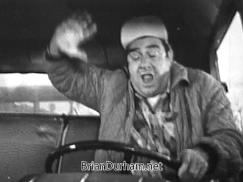 The still depicts a man in a truck, appearing animated and distressed, possibly reacting to a humorous or chaotic situation. He is gripping the steering wheel with a look of exaggerated surprise or fear, suggesting a comedic or lighthearted context typical of vintage commercials. The black-and-white format accentuates the retro style of the 1968 Red Rose Tea advertisement.