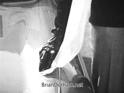 The still from the 1968 Red Rose Tea commercial features a close-up of a hand wearing a black glove, holding a white cloth. The background suggests a car's surface, likely indicating a scene involving care or service. The overall aesthetic reflects the style of advertisements from that era, combining everyday moments with product promotion.