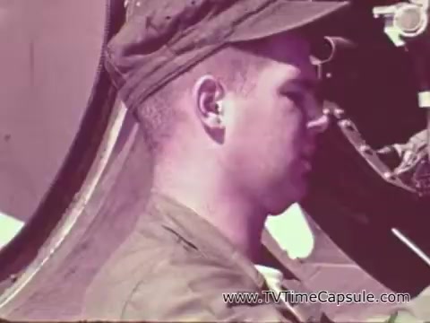 The still features a young Marine, dressed in a military uniform and cap, engaged in work or maintenance on military equipment. The image suggests a focus on discipline and training, characteristic of Marine Corps promotional materials during the Vietnam era. The color tone is likely vintage, reinforcing the historical context.