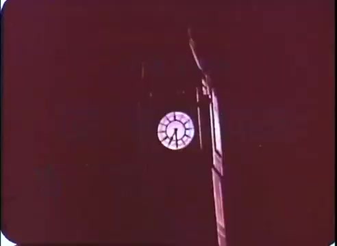 The still depicts a clock tower with a prominent clock face, likely symbolizing the passage of time, which is central to the theme of 'The Time Machine.' The image has a warm, reddish tint, enhancing a sense of nostalgia or urgency. The clock hands indicate a specific time, suggesting a pivotal moment in the narrative. The overall composition emphasizes the importance of time in the story.