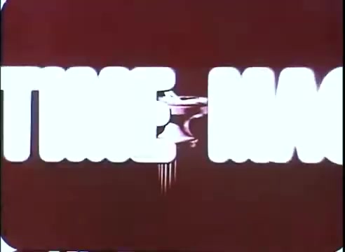 The still features a stylized title sequence for 'The Time Machine,' highlighted with bold, white lettering against a deep red background. The letters appear slightly distorted, possibly conveying a sense of motion or transition. An accompanying graphic element, resembling a mechanical device or time machine, adds a futuristic touch. The overall aesthetic reflects mid-20th century design, capturing the film's sci-fi essence.