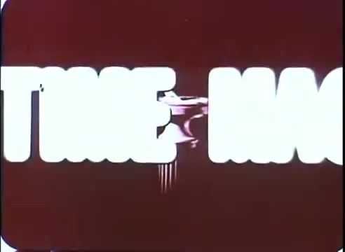 The 16mm still features bold, stylized text reading 'TIME MACHINE,' with a gradient color backdrop that transitions from red to a lighter hue. The letters are thick, emphasizing a retro aesthetic typical of promotional material from the era. A visual motif resembling a time machine apparatus can be discerned, adding to the science fiction theme. The overall composition conveys a sense of excitement and intrigue about the film.