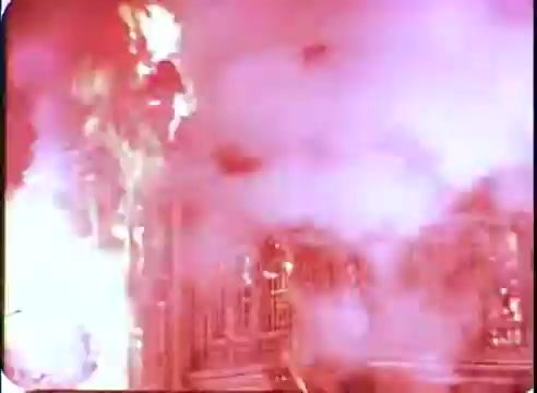 The still from 'The Time Machine' promos features a dramatic scene with intense flames and smoke, creating a sense of chaos and urgency. The vibrant colors suggest a fantastic and explosive moment, characteristic of sci-fi cinema. The background appears to depict an elaborate, possibly futuristic setting, emphasizing the film's themes of time travel and adventure.