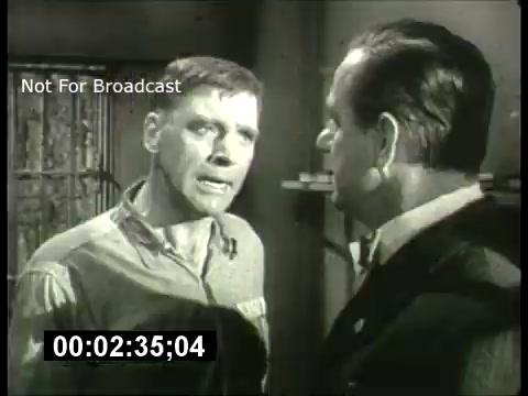 The still features two male characters in a dramatic exchange. One character, wearing a prison uniform, appears agitated, while the other, dressed in formal attire, seems composed but intense. The setting suggests a confrontation, likely taking place in a confined space, such as a jail cell. This moment encapsulates the tension commonly found in suspenseful narratives of the 1960s, fitting the tone of 'ABC Sunday Night Movie' promos from that era. The image also includes a timestamp and the note 'Not For Broadcast.'