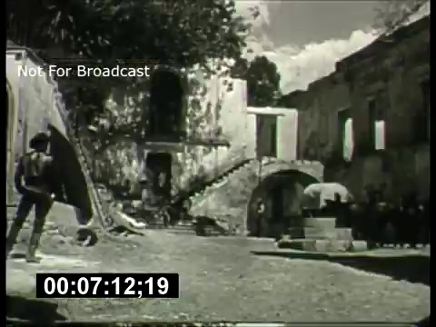 The still depicts a black-and-white scene likely from the 1960s, showcasing a rustic courtyard with stone architecture. Characters appear engaged in an activity, possibly a dramatic or cinematic moment. The setting hints at historical or possibly Western themes, typical of that era's movie promos. The overlay indicates it is not for broadcast, and a timecode is visible, suggesting a specific moment captured from the film reel.