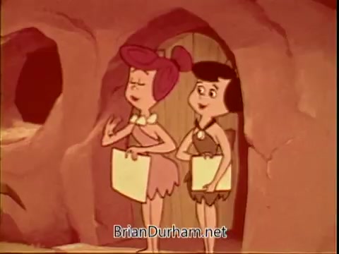The still features two animated characters from 'The Flintstones,' likely Wilma Flintstone and her friend Betty Rubble, standing outside a cave. They appear to be engaged in a conversation, holding white papers. The color palette has a warm, vintage tone, characteristic of 16mm film. This scene is part of a public service announcement for the American Cancer Society.