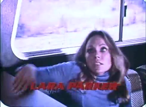 The still from the trailer for 'Race with the Devil' features a woman looking anxiously, her hand resting on a surface as she leans forward. The scene appears to be set inside a vehicle, with hints of movement or urgency reflected in her expression. The text overlay indicates the name 'Lara Parker.' The visuals capture a tense moment amidst the film's themes of suspense and danger.