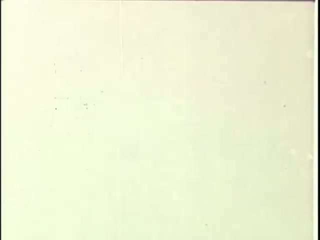 The still likely features a blank or minimal visual composition, typical of leader tape used in film editing. This frame could show an unmarked or very lightly textured background, possibly indicating it’s a transitional shot or the beginning of a reel. Such footage often serves as a placeholder before the actual content begins, focusing on the specifics of tape-to-film transfers.