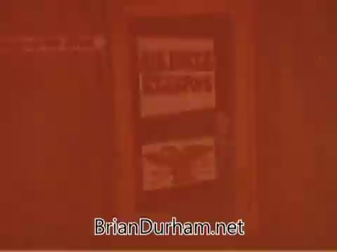 The still from the 1960s Air Force Reserve PSA features a reddish tint, showcasing a display board with various promotional materials related to the Air Force Reserve. The text and visuals emphasize service and recruitment messages aimed at the audience. The overall tone suggests a focus on patriotism and civic duty.