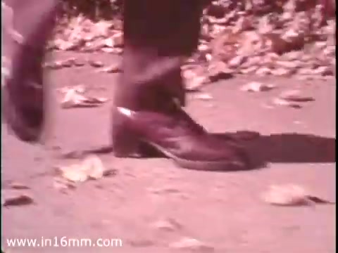 The still from the 'Sole Leather Council Bicentennial PSA - 1975' features a close-up of polished shoes walking on a leaf-strewn path. The emphasis is on the act of walking, promoting the message of conservation with the slogan 'Save gas! Use shoe leather instead!' The visual captures a nostalgic, vintage feel typical of the 16mm format.