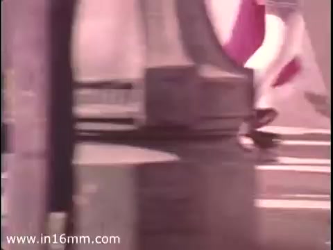 The still from 'Sole Leather Council Bicentennial PSA - 1975' shows a person walking, emphasizing the message of using shoes instead of cars to save gas. The 16mm print captures a candid moment on a street, likely featuring urban elements and movement. The visual effectively conveys the PSA's theme of promoting walking over driving.