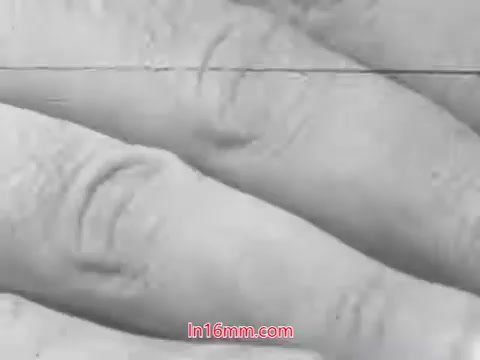 The 16mm still from 'Check for Tire Wear!' features a close-up of a hand examining tire tread. The focus on the fingers suggests a demonstration or instructional context, emphasizing the importance of checking tire wear for safety. The image likely captures a moment from a public service announcement aimed at promoting vehicle safety practices in the 1960s.