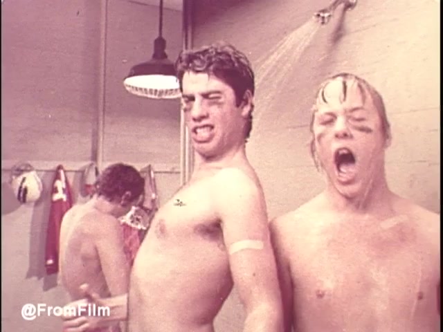 The still from the 1970s Band-Aid commercial features two young men in a shower setting, humorously expressing themselves. They appear to be playfully tugging at each other, with one actor making a funny face while the other yells, possibly in jest. They both sport Band-Aids on their arms, reinforcing the playful theme of the jingle 'I am stuck on Band-Aids 'cause Band-Aid's stuck on me.' The image captures the lighthearted and fun spirit of the era. Follow @FromFilm for more!