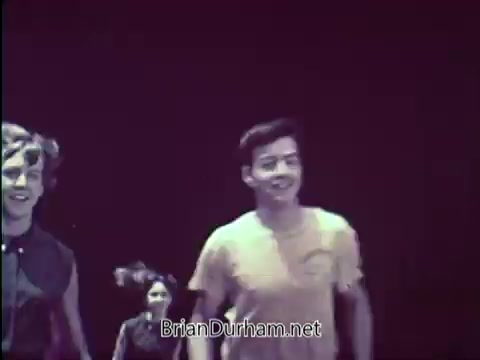 The still features a group of young people, including two boys and a girl, smiling and running towards the camera. They appear to be engaged in a fun, active pursuit, highlighting themes of physical fitness and youth. The background is dim, focusing attention on the individuals and their joyful expressions, characteristic of the 1960s promotion of fitness and health.