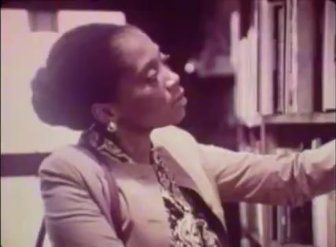 The still shows a woman in a bookstore, engaged in browsing books. She has a thoughtful expression, suggesting she’s considering her options. The environment is conducive to reading, with shelves lined with books. The overall tone is warm and inviting, typical of promotional material aimed at encouraging local services, in this case, Job Service Nebraska.