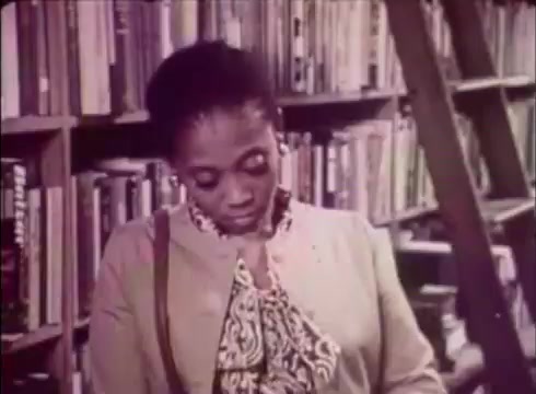 The still from 'Job Service Nebraska - Book Store' features a woman looking down thoughtfully, surrounded by bookshelves filled with various titles. The setting suggests a cozy, inviting atmosphere typical of a bookstore, indicating a theme related to education and job resources. This 16mm print captures a candid moment, emphasizing the individual's engagement with literature, likely in the context of career development and support services offered by Job Service Nebraska.
